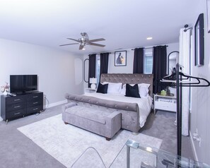 A modern bedroom with a bed, a TV, a dresser, and a ceiling fan. - Spacious 4-bedroom 3 bath building in lovely Danville with AC (Danville)