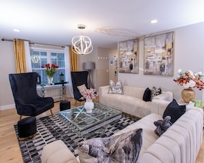 A modern living room with a glass coffee table, two sofas, and a chandelier. - Spacious 4-bedroom 3 bath building in lovely Danville with AC (Danville)