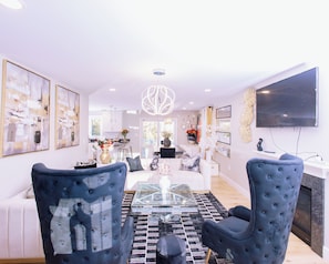 A modern living room with a glass coffee table, blue upholstered chairs, and a chandelier. - Spacious 4-bedroom 3 bath building in lovely Danville with AC (Danville)