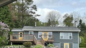 A two-story house with a balcony, a front porch, and a stone wall. - Spacious Chester Home with Spectacular Ocean Views! (Chester)