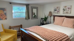A bedroom with a bed, a chair, a window with curtains, a lamp, and wall art. - Spacious Chester Home with Spectacular Ocean Views! (Chester)