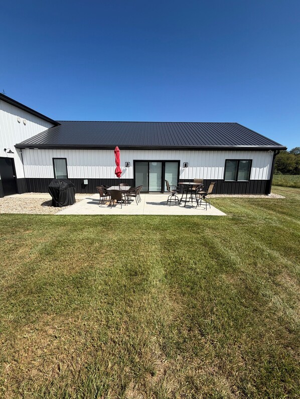 A modern building with a flat roof, a covered patio area with outdoor furniture, and a well-maintained lawn.