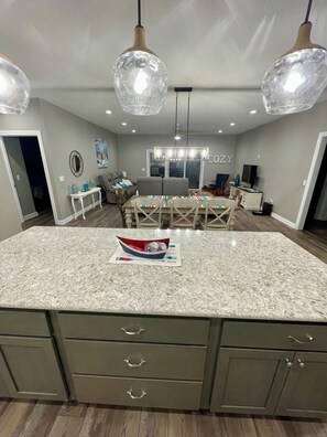 A modern kitchen with a granite countertop, built-in cabinets, and pendant lighting.