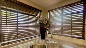 A kitchen with two sinks, a stainless steel faucet, and a vase with flowers.