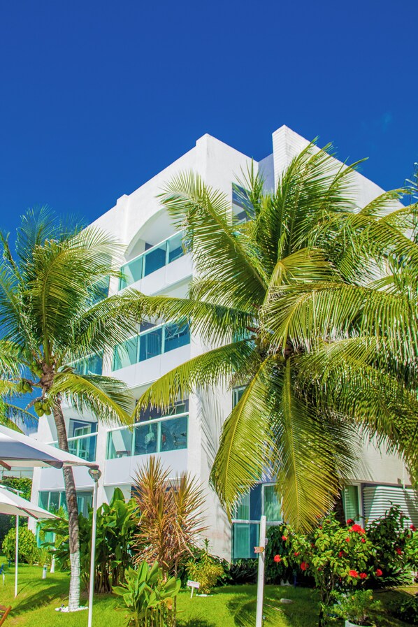 A modern building with multiple floors, surrounded by lush greenery and palm trees.