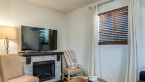 Uma sala de estar com lareira, televisão, sofá e mesa de centro.