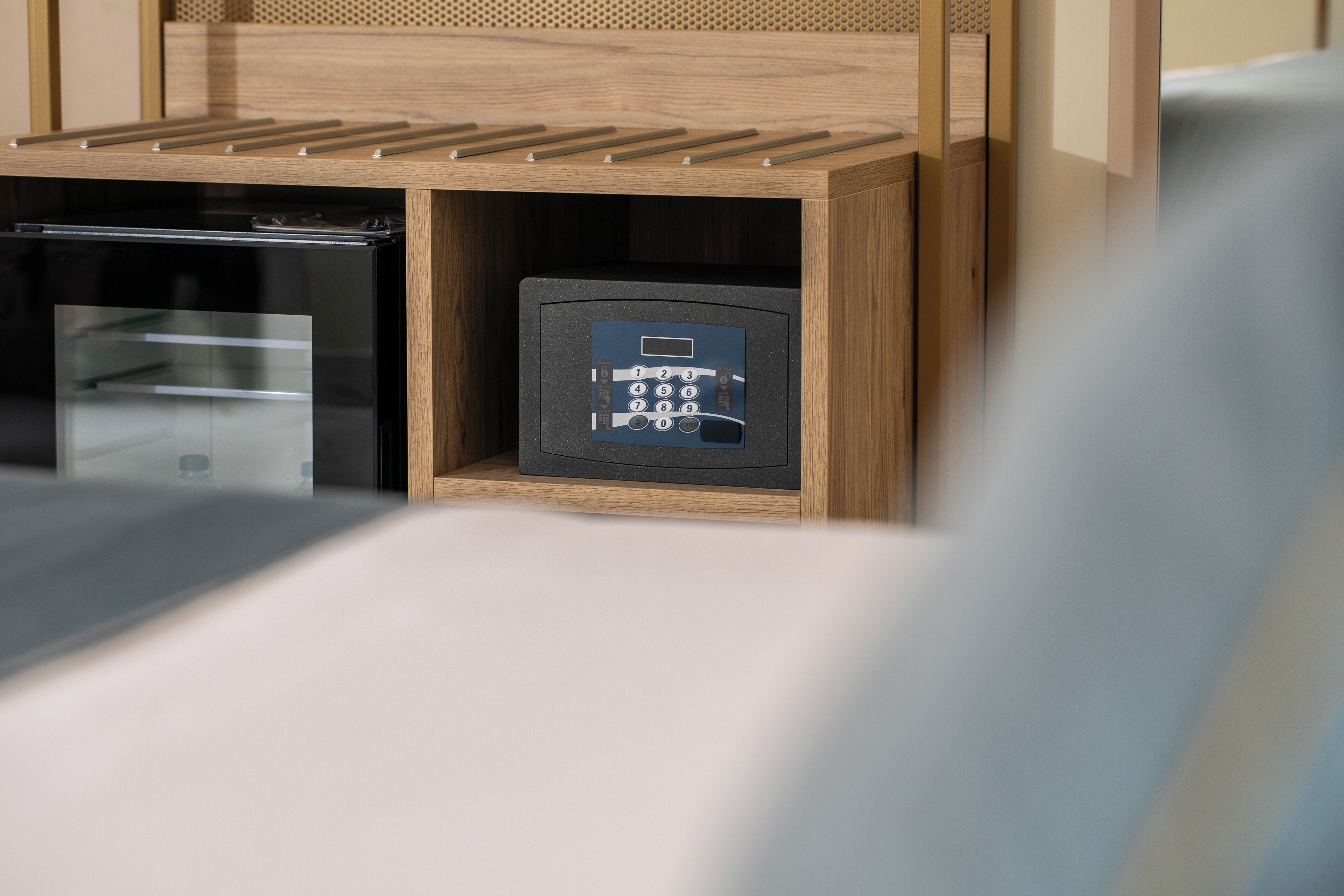 Ein Holzkorpus mit fest eingebautem Safe und einem kleinen Gerät, vermutlich einer Kaffeemaschine, in einem Hotelzimmer.
