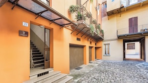 A narrow alleyway with a cobblestone path, a staircase leading to a building entrance, and a balcony with plants. - La Casa delle Dee – Self Check-in (Bologna)