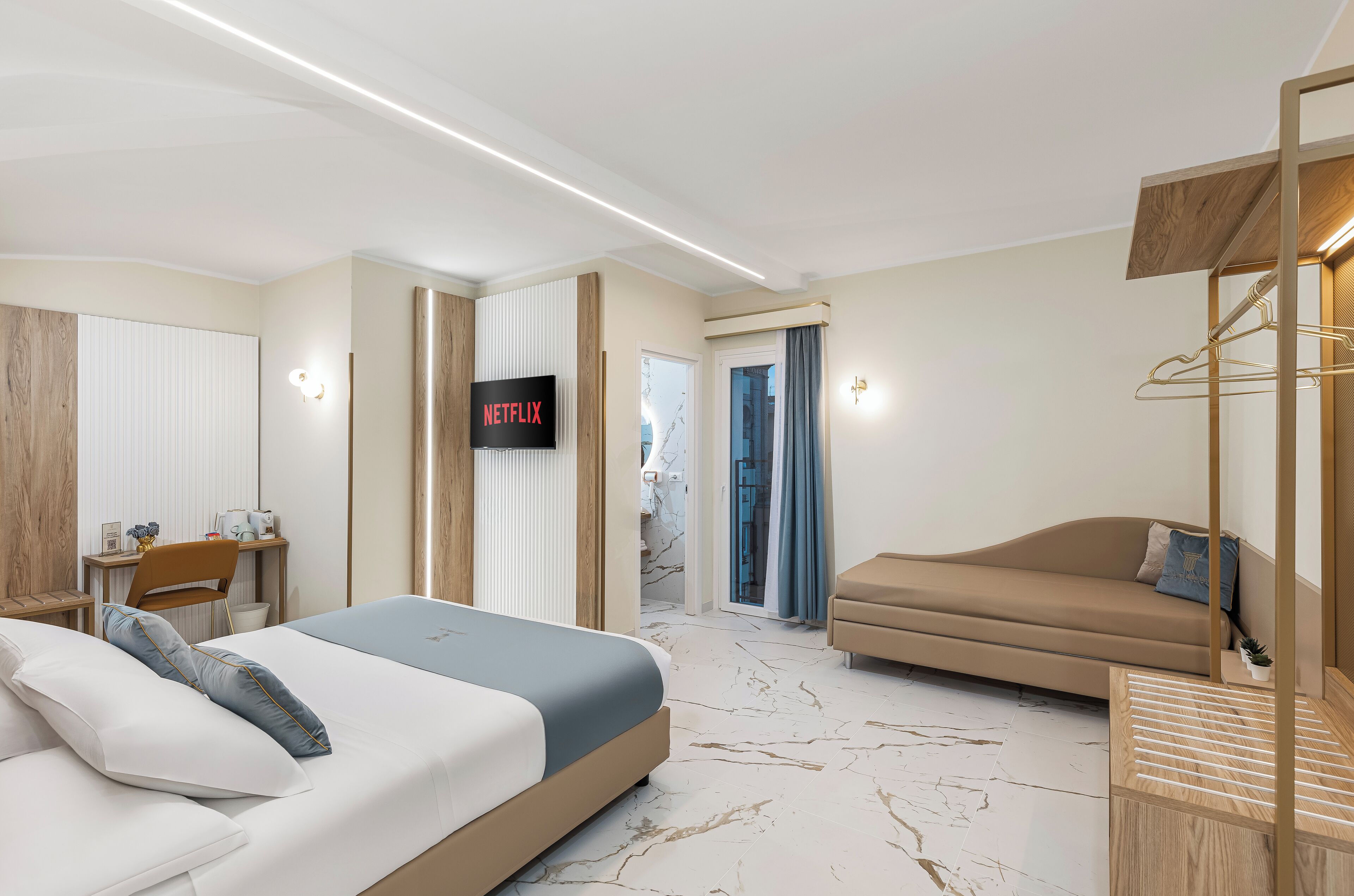 Una habitación de hotel moderna con cama, sofá, televisor y escritorio.