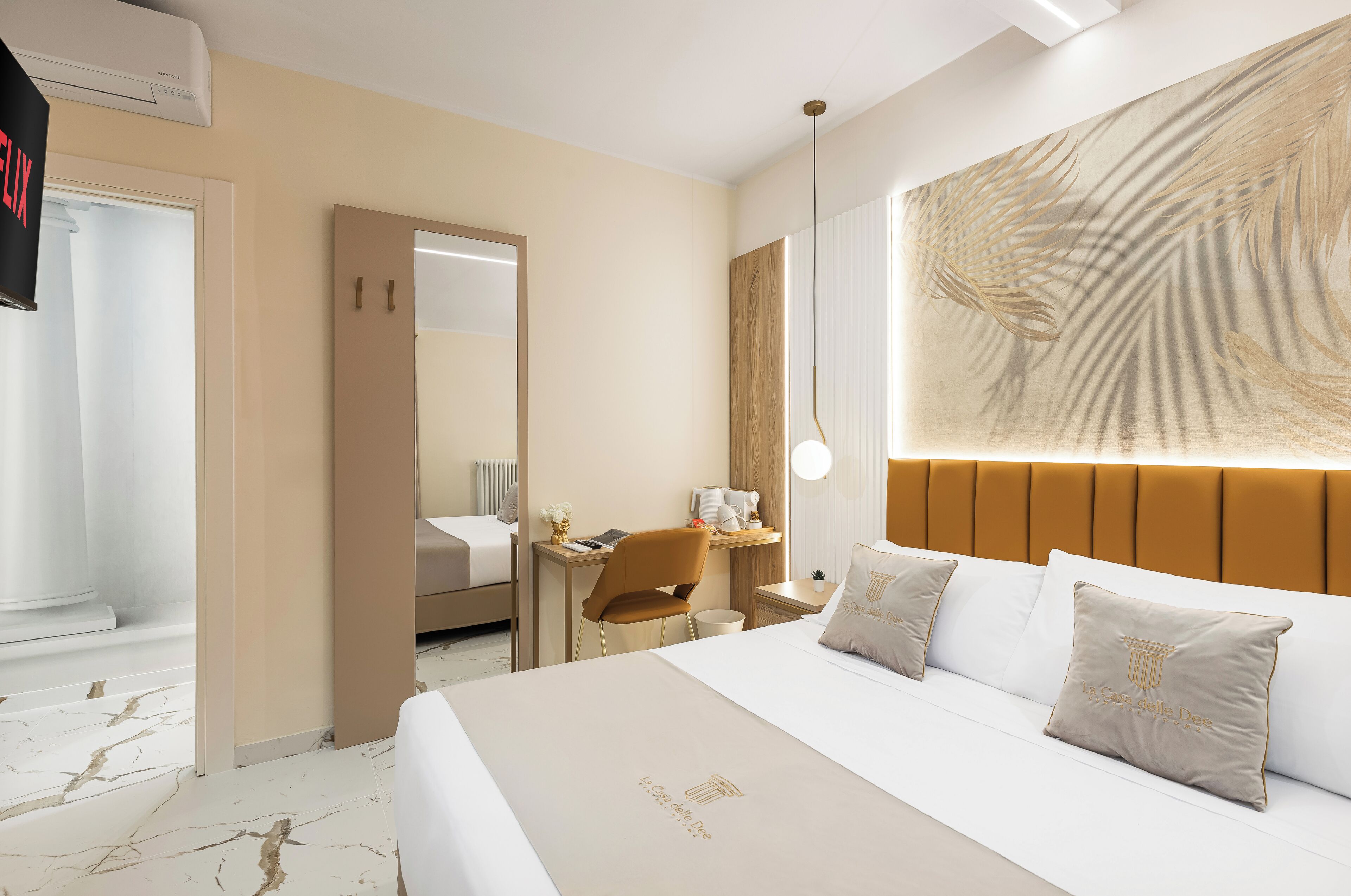Ein Hotelzimmer mit einem großen Bett, einem Schreibtisch, einem Stuhl und einer großflächigen Wandmalerei.