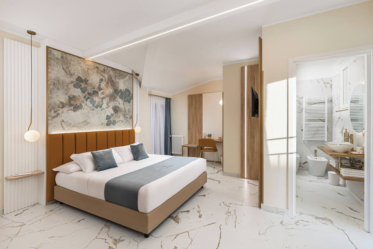 Ein modernes Schlafzimmer mit einem großen Bett, einem Schreibtisch und einem Badezimmer mit Marmorboden.