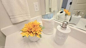 Une salle de bain avec un lavabo blanc, une serviette blanche et un miroir qui reflète la salle de bain.