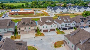 A residential area with detached houses, a commercial building, and a clear sky. - The Tigers Pathway House near LSU Stadium - BC1034 (Baton Rouge)