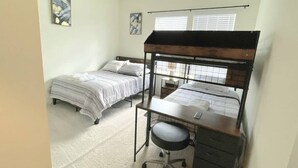 A dormitory room with bunk beds, a desk, and a chair. - The Tigers Pathway House near LSU Stadium - BC1034 (Baton Rouge)