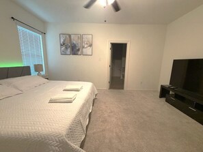 A bedroom with a bed, a television, and a door leading to another room.