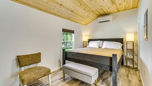 Ein Schlafzimmer mit Holzboden, einem Bett mit Holz Kopfteil, einer Bank und einem Nachttisch mit Lampe.