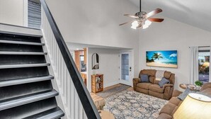 Un salon spacieux avec un grand canapé, un ventilateur de plafond et une vue sur l’extérieur.