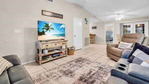 Un salon équipé d’un téléviseur, d’un canapé, d’une table basse et d’un ventilateur de plafond.