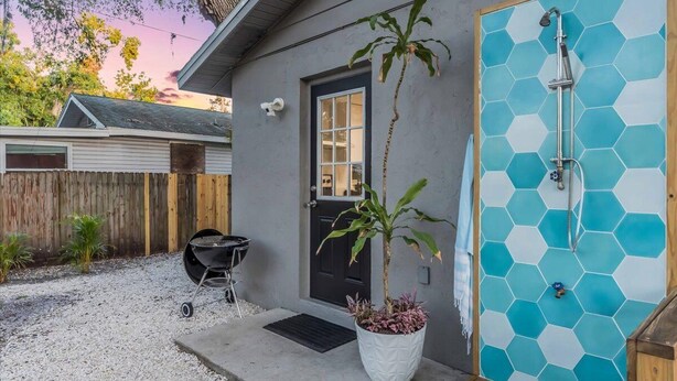 A house with a grey exterior, a black door, and a hexagonal patterned shower enclosure. - CandyPop Retro Retreat | Ms Pac-Man Game + Patio (Sarasota)