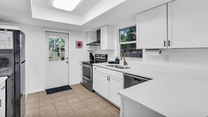 A modern kitchen with white cabinets, a built-in oven, and a stainless steel refrigerator. - CandyPop Retro Retreat | Ms Pac-Man Game + Patio (Sarasota)