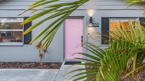 A modern house with a pink door, a number 213 sign, and a small garden with palm plants. - CandyPop Retro Retreat | Ms Pac-Man Game + Patio (Sarasota)