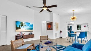 A modern living room with a round coffee table, blue sofa, and a ceiling fan. - CandyPop Retro Retreat | Ms Pac-Man Game + Patio (Sarasota)