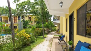 A hotel courtyard with a pool, outdoor seating, and lush greenery. - Lovely modern 2 bedroom gated condo, walk to the beach and town center (Playas del Coco)