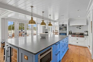 Una cocina amplia con una isla grande, armarios blancos y piso de madera.