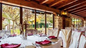 Un comedor con mesas redondas, manteles blancos y servilletas rojas.