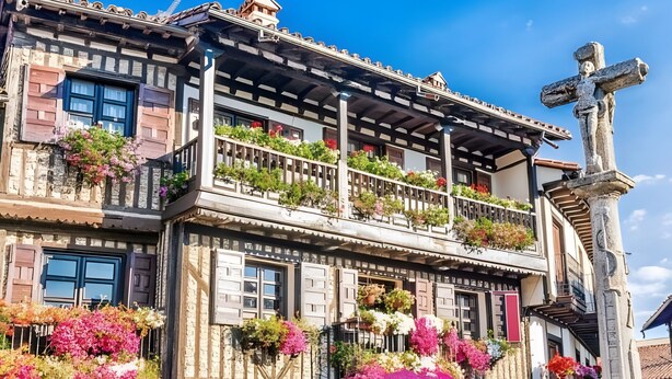 Un edificio histórico con un balcón, una cruz de piedra y una fachada tradicional.