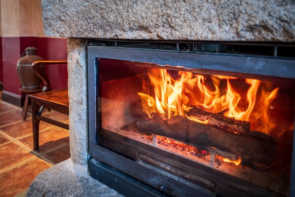 A stone fireplace with a visible fire burning inside.