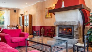 A living room with a fireplace, red sofas, a glass coffee table, and a stone fireplace surround.