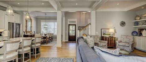 A spacious living area with a large blue sofa, a dining table with chairs, and a kitchen area with modern appliances.