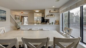 Cozinha moderna com ilha central, eletrodomésticos embutidos e uma grande janela com vista para o exterior.