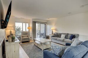 A living room with a sofa, armchair, coffee table, and a TV mounted on the wall. - Spacious 3BR, 3.5BA condo in South Forest Beach, Hilton Head Island, perfect for 8 guests. (Hilton Head Island)