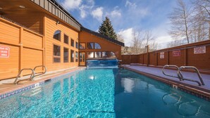Une piscine à l’eau d’un bleu cristallin, avec une terrasse en bois et un espace abrité.