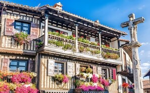 Un bâtiment historique doté d’un balcon, d’une croix en pierre et d’une façade de style traditionnel.