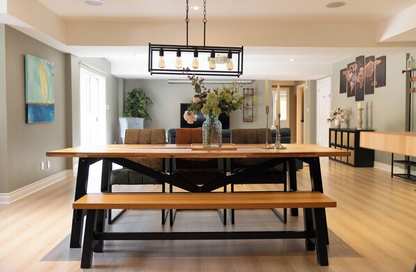 Un espace repas avec une table en bois, des bancs et un luminaire suspendu.