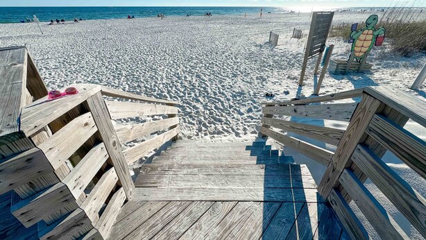 A wooden staircase leading to a beach with a turtle sign.