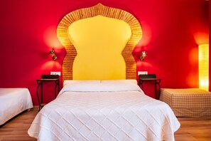Ein Hotelzimmer mit einem großen Bett, zwei Nachttischen, einer roten Wand und einem auffälligen, gelben Kopfteil.