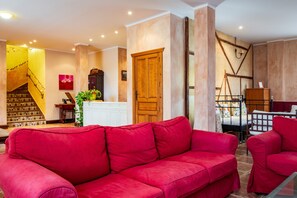 Ein Wohnzimmer mit rotem Sofa, Holztür, Treppe und Bett mit Holz Kopfteil.