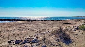 Une plage bordée d’un rivage rocheux, avec un ciel dégagé et une mer calme.