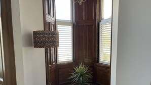 A corner of a room with a wooden door, a potted plant, and a wall-mounted lamp.