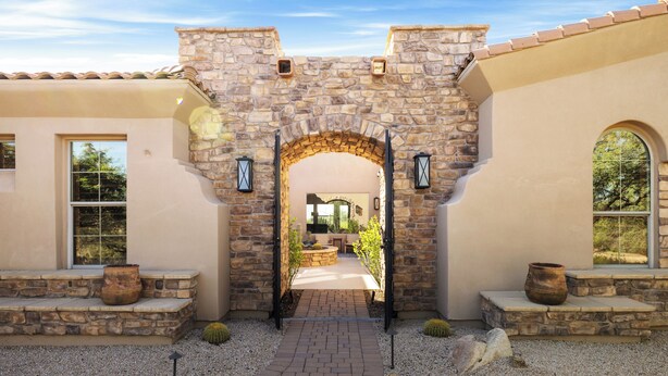 A stone archway leading to a patio area with seating and planters. - Desert Oasis with Pool & Black Mountain Views! (Scottsdale)