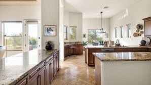 A spacious kitchen with granite countertops, wooden cabinets, and a large island. - Desert Oasis with Pool & Black Mountain Views! (Scottsdale)