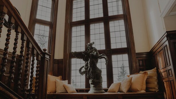 A grand staircase with wooden balusters, a large window with multiple panes, and a bench with cushions. - Experience Divine Serenity, Nature & Luxury - Unite. Rest. Reflect. Restore (Pembroke)