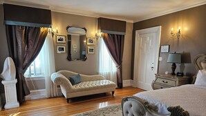 A bedroom with a large bed, a nightstand with a lamp, a dresser, a mirror, and a decorative bust. - Experience Divine Serenity, Nature & Luxury - Unite. Rest. Reflect. Restore (Pembroke)