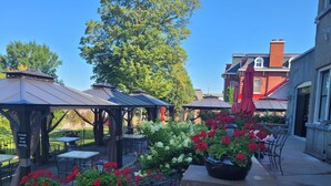 An outdoor patio area with tables and chairs, a gazebo, and potted plants. - Experience Divine Serenity, Nature & Luxury - Unite. Rest. Reflect. Restore (Pembroke)