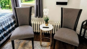 A room with a bed, two armchairs, a small table with a plant, a round mirror, and a radiator. - The Buffalo Loft- 3BR Upstairs Apartment • Pet-Friendly • Outdoor Patio &... (Buffalo)