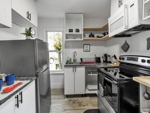 A modern kitchen with white cabinetry, a stainless steel refrigerator, a black stove, and a wooden countertop. - The Buffalo Loft- 3BR Upstairs Apartment • Pet-Friendly • Outdoor Patio &... (Buffalo)